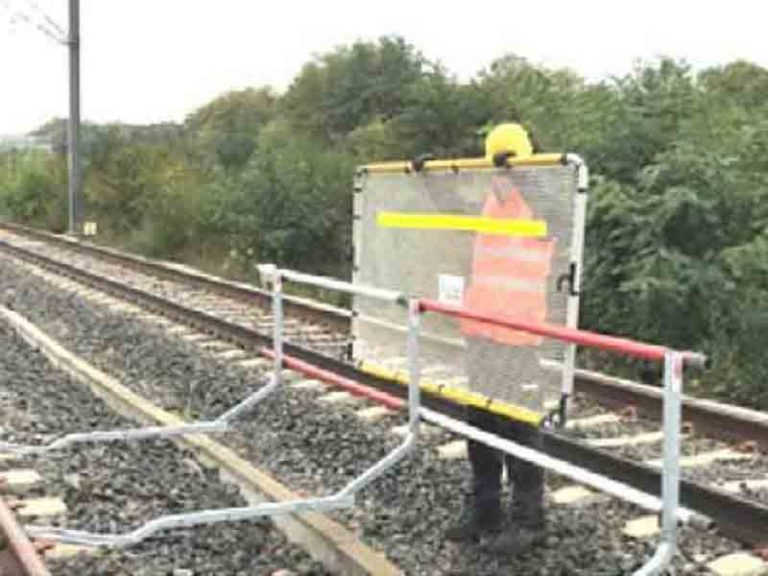 agent posant une barrière limitative sur voie ferroviaire